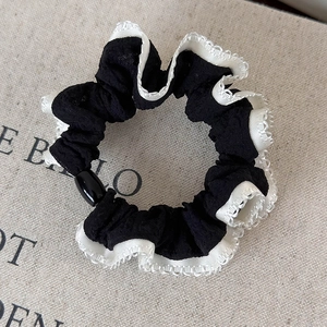Close-up of black and white lace scrunchie with polka dots and shiny decorative bead