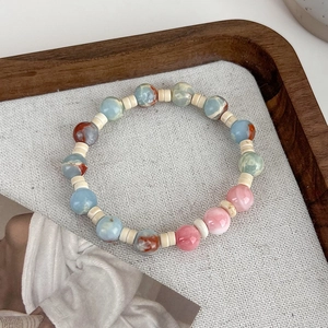 Close-up of pink and blue faux shoushan stone beaded bracelet on wooden tray