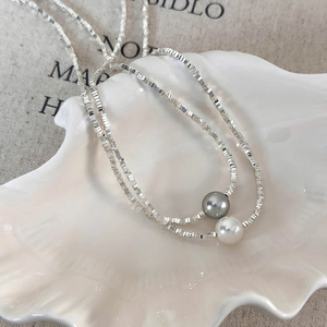 Detail of double-layer silver bead necklace with white and dark grey pearls on shell plate