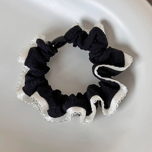 Macro view of French retro black fabric scrunchie with white lace edges and buckle