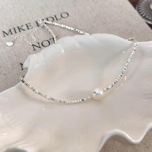 Detail of silver box chain necklace with white pearl in a shell jewelry tray