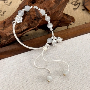 Détail du bracelet muguet avec pierre œil de chat sur support en bois ancien