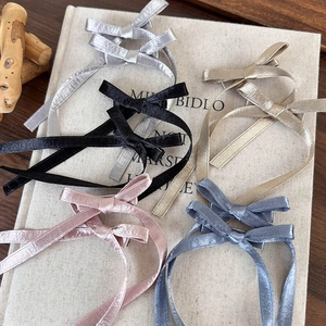 Barrettes à nœuds élégantes en satin en cinq couleurs sur fond de livre vintage