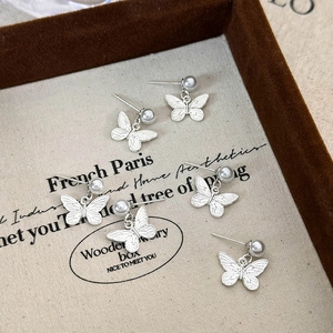 Elegant butterfly pearl stud earring set in silver finish on a luxury jewelry tray