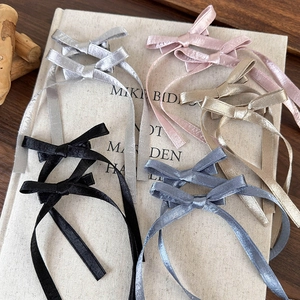 Détail de cinq pinces à cheveux nśud de ballet en tissu brillant avec de longs rubans fins