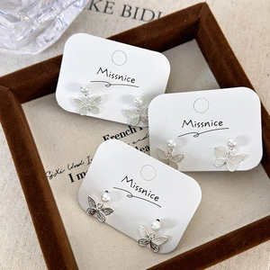 Elegant butterfly pearl earrings set in silver finish on a premium display card