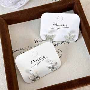 Elegant butterfly pearl stud earrings in silver minimalist design on display card