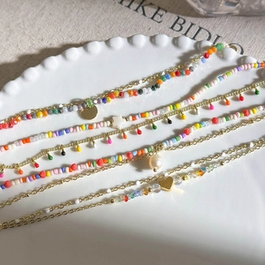 Detail of colorful layered beaded bracelets with pearls and gold star charms on lace plate