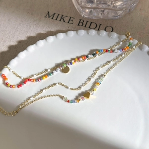 Detail of double-layered beaded bracelet with colorful faceted beads and golden heart charms