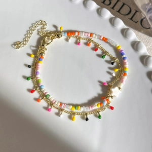 Detailed view of double-layer beaded bracelet with colorful charms and star bead on white plate