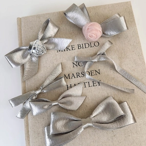 Detailed view of silver satin bow hair clips set with metallic rose floral designs