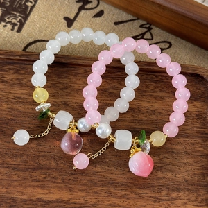 Bracelets à pendentif pêche avec cristaux et perles roses dans un plateau en bois chic