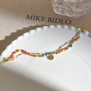 Double-layer gold chain bracelet with colorful beads and a circular pendant detail