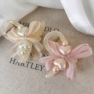Elegant cream and pink bow hair claws with pearl heart accents on satin fabric
