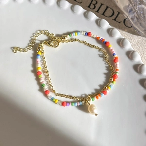 Close-up of double-layer colorful beaded bracelet with gold chain and pearl pendant