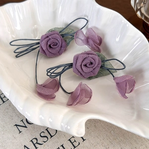 Detailansicht der lila Chiffon-Rosenblüten und grünen Blätter an diesem handgemachten Haargummi