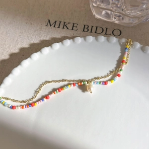 Detail of a double-layer beaded bracelet with a pearl pendant on a white ceramic plate