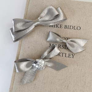 Detailed macro view of silver metallic satin bow hair clips with rose texture details