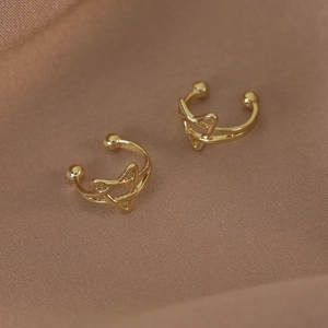 Détail des boucles d'oreilles étoiles dorées sur tissu texturé au design élégant