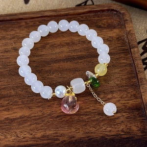 Détail du bracelet perlé avec pendentif pêche, perles blanches et accents dorés