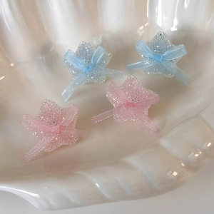 Pink and blue sugary star stud earrings with ribbon bows displayed in a seashell tray