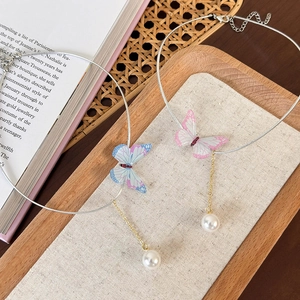 Détail de pendentifs papillons colorés avec perles sur colliers ras du cou élégants