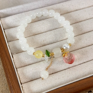 Bracelet à perles doux avec pendentif pêche et accents dorés dans un écrin à bijoux