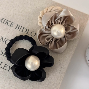 Detail view of satin camellia hair ties in black and champagne with large pearls
