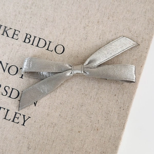 Detailed macro view of the silver silk ribbon bow hair clip with fine shimmering texture