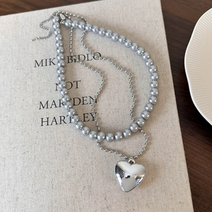 Détail d'un collier double rang en perles argentées et perles lilas avec pendentif cœur