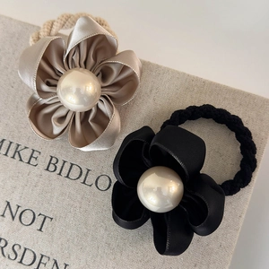 Detail showing satin camellia flower hair ties with large pearls in black and champagne