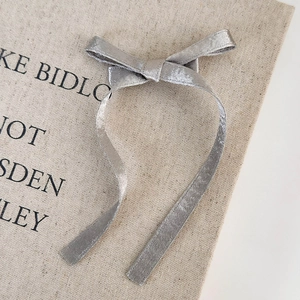 Detail of silver silk-textured ribbon bow hair clip on rustic fabric background