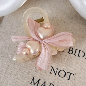 Macro detail of silk pink bow hair claw clip with heart shaped accents and pearls