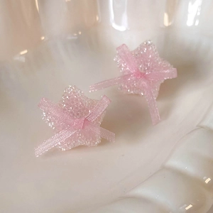 Detail of pink sugar-coated star earrings with a delicate sheer ribbon bow decoration