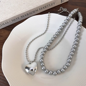 Collier à pendentif cœur argenté avec perles grises et chaîne à billes sur plat céramique