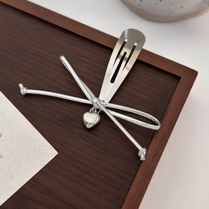 Détail de la pince à cheveux avec pendentif cœur argenté et nœud en ruban satin