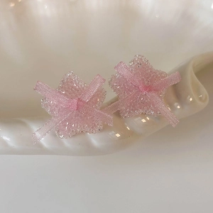 Macro detail of pink star earring with sugar crystal texture and ribbon bow decoration