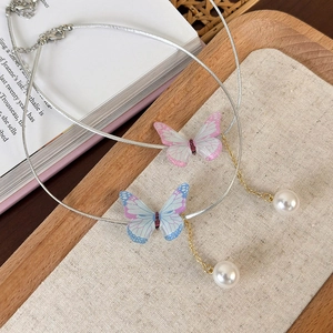 Détail de colliers choker papillon irisé avec glands de perles sur plateau en bois