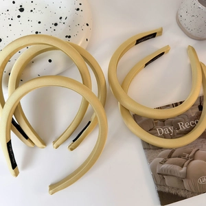 Gros plan détaillé du serre-tête rembourré en satin jaune clair montrant la texture lisse