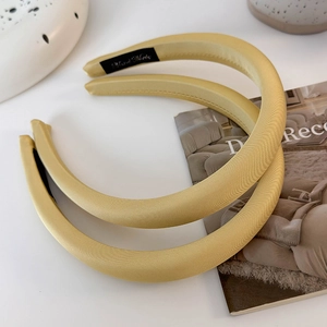Détail d'un serre-tête épais en satin jaune avec une étiquette intérieure fait main