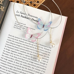Parure choker papillon élégante avec pendentifs dégradés et perles sur livre vintage