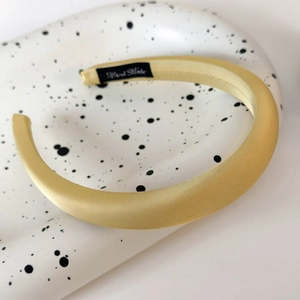 Vue détaillée du serre-tête en satin jaune avec rembourrage épais et étiquette Hand Made