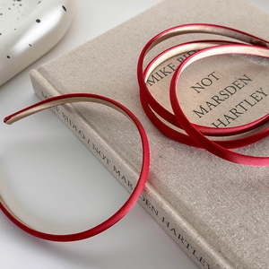 Close-up of a red satin thin headband with gold lining on a textured background book
