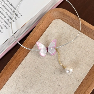 Détail d'un pendentif papillon avec perle sur un collier choker en métal argenté