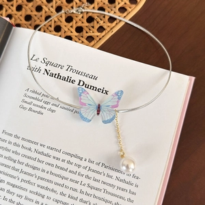 Détail du collier choker papillon aux ailes irisées avec pampille en perle élégante