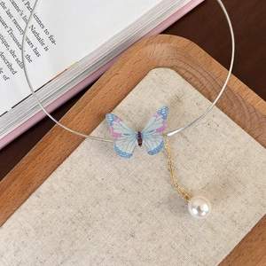 Détail du collier choker papillon coloré avec pampilles de perles sur fond vintage