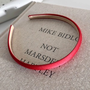 Detailed view of red satin thin headband with beige non-slip lining on book background