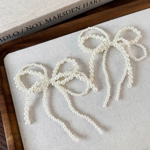 Détails de breloques élégantes en perles avec nœuds et pompons sophistiqués