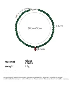 Close-up of green glass bead necklace with red teardrop pendant and size specifications