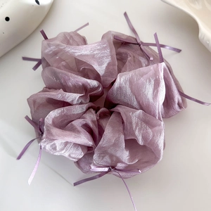Dettaglio dell'elastico per capelli in tulle viola con fiocchi e nastri su sfondo bianco